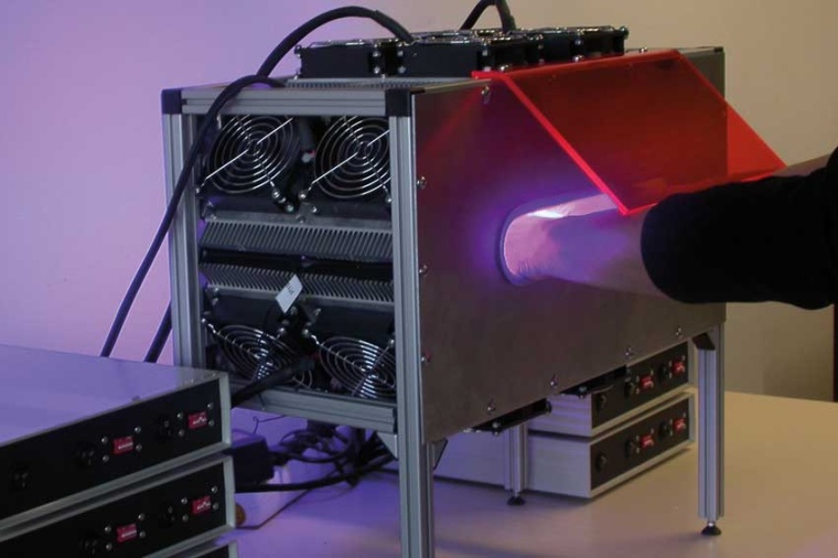 Hand disinfection device with glare shield (orange) during use. (Source: GMBU)