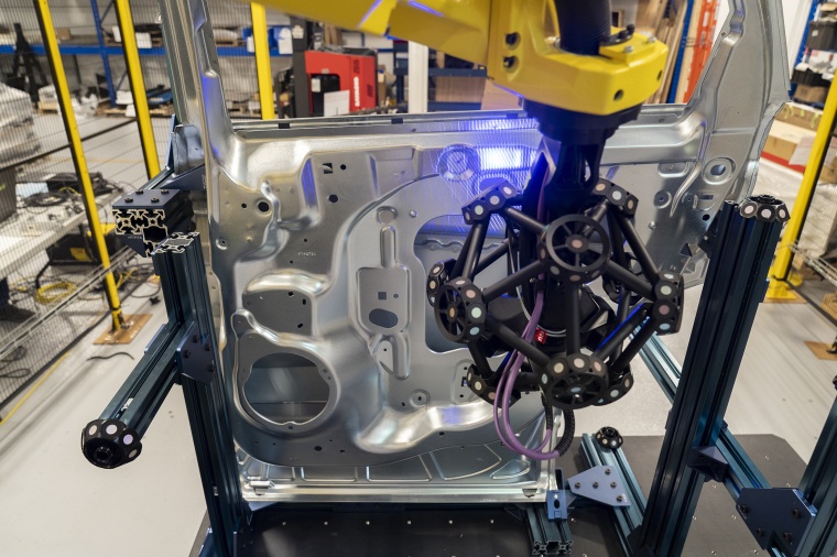 A robot-mounted optical CMM scanner during quality control of a car door....