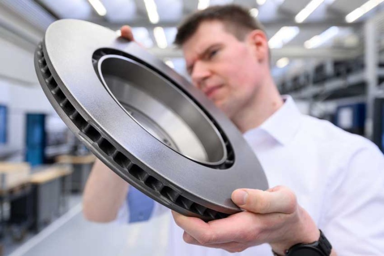 Employee holding a coated brake disc (Source: Trumpf)
